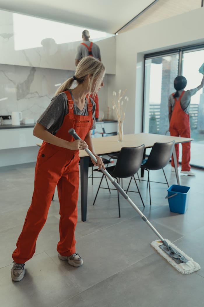 hero-img Cleaning team in red overalls mopping and sanitizing a modern home interior.